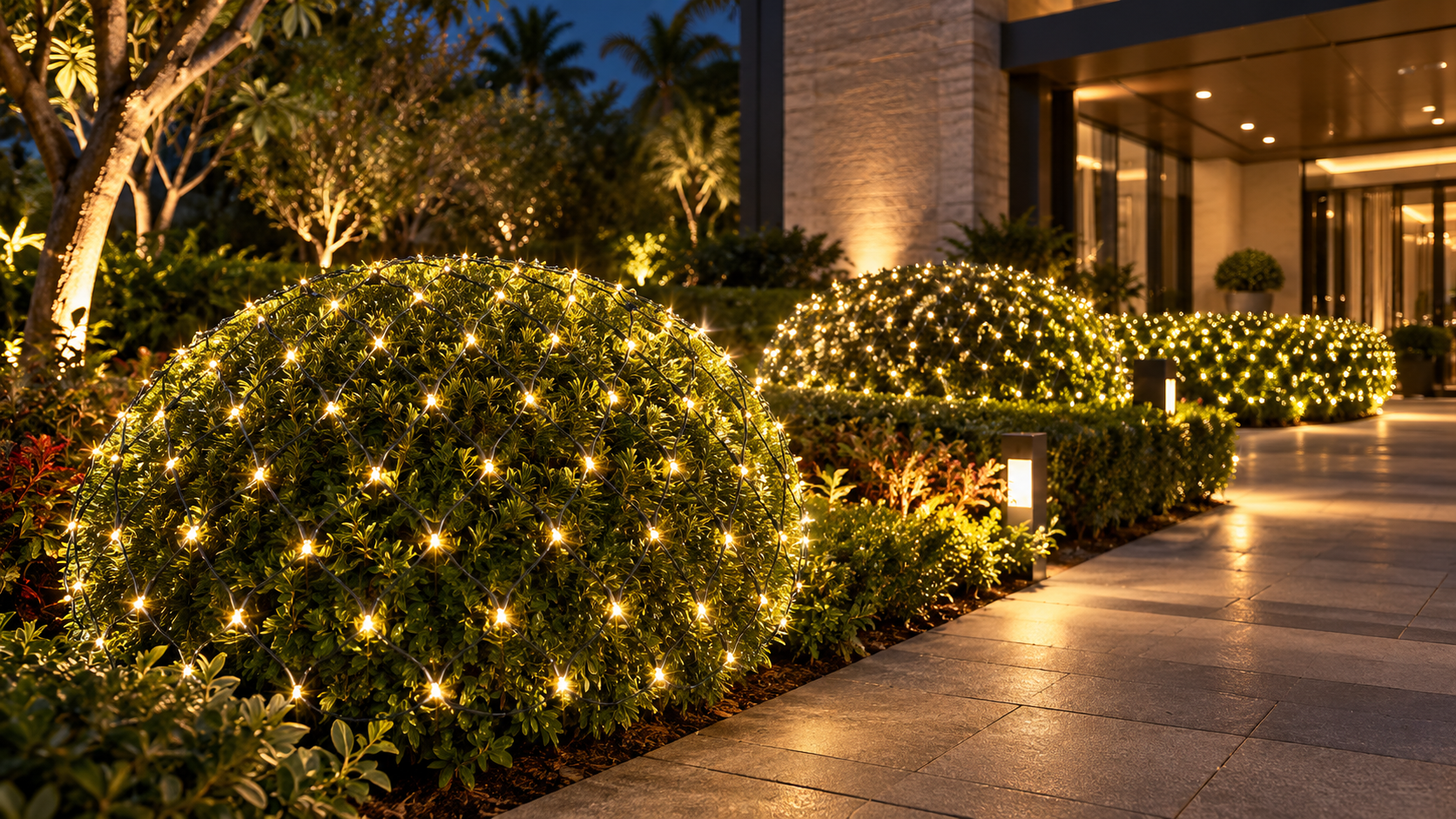 Warm white outdoor net string lights illuminating landscaped shrubs
